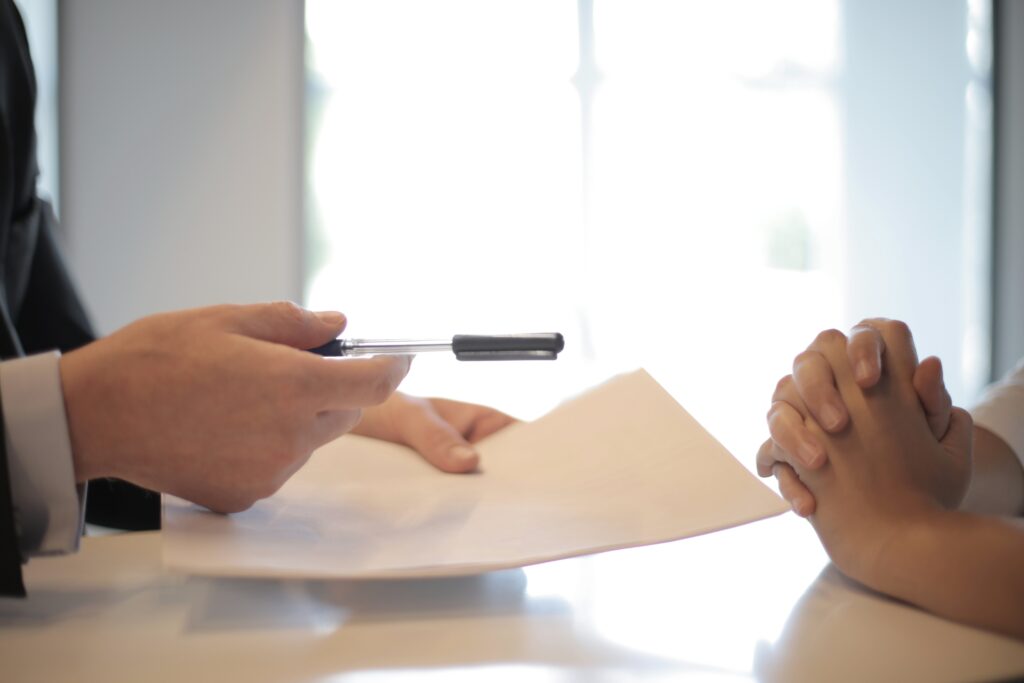 A professional holding a paper and pen and client with their hands on the table